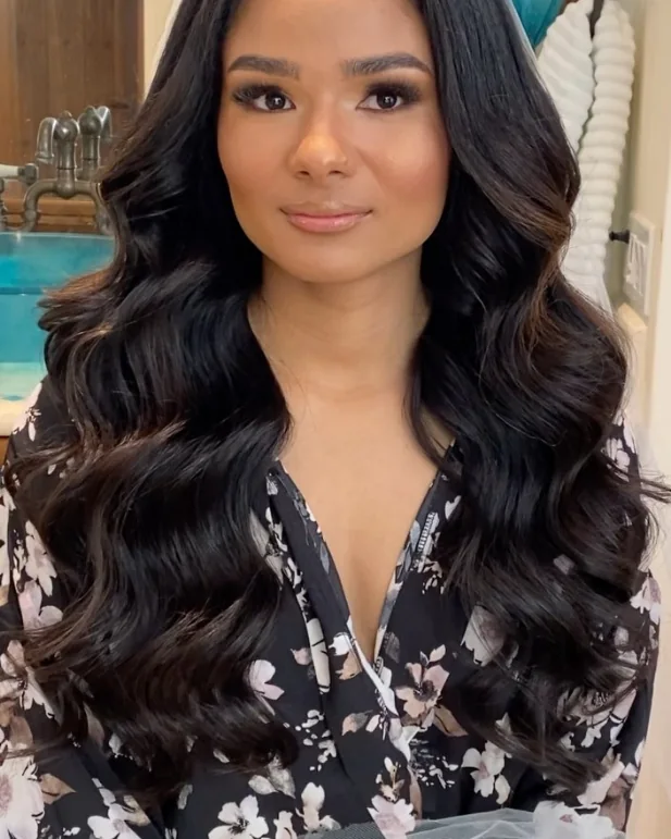 A bride with deep brown skin, soft glam makeup and long glossy waves.