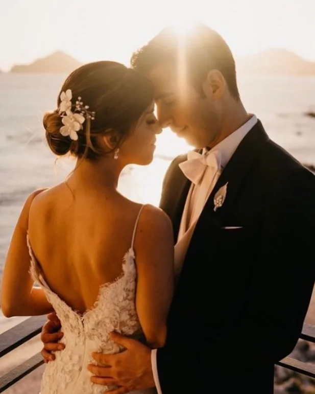 A couple touching foreheads at golden hour by the sea.