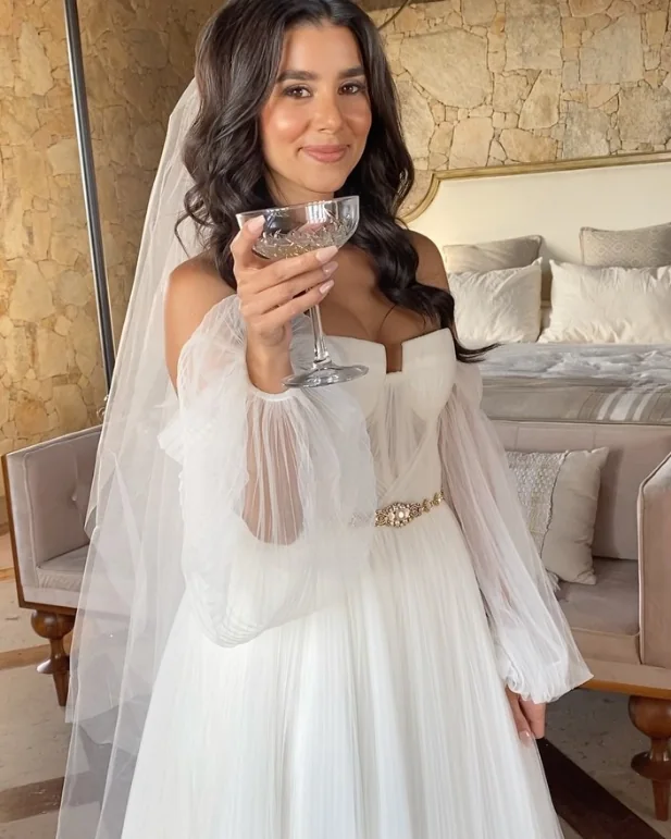 A bride in her gown raising a coupe of champagne.