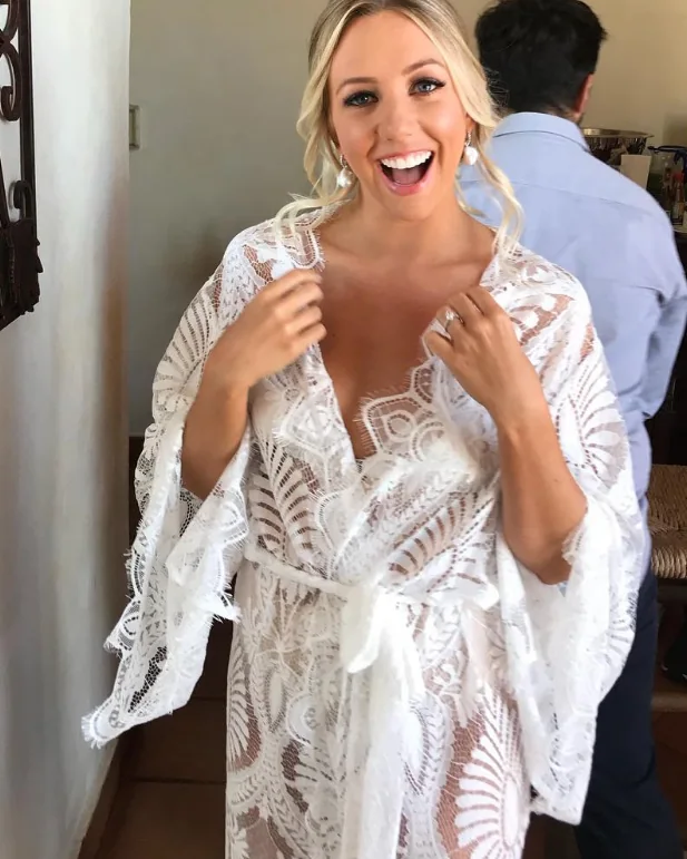 A bride laughing in a lace robe on her wedding morning.